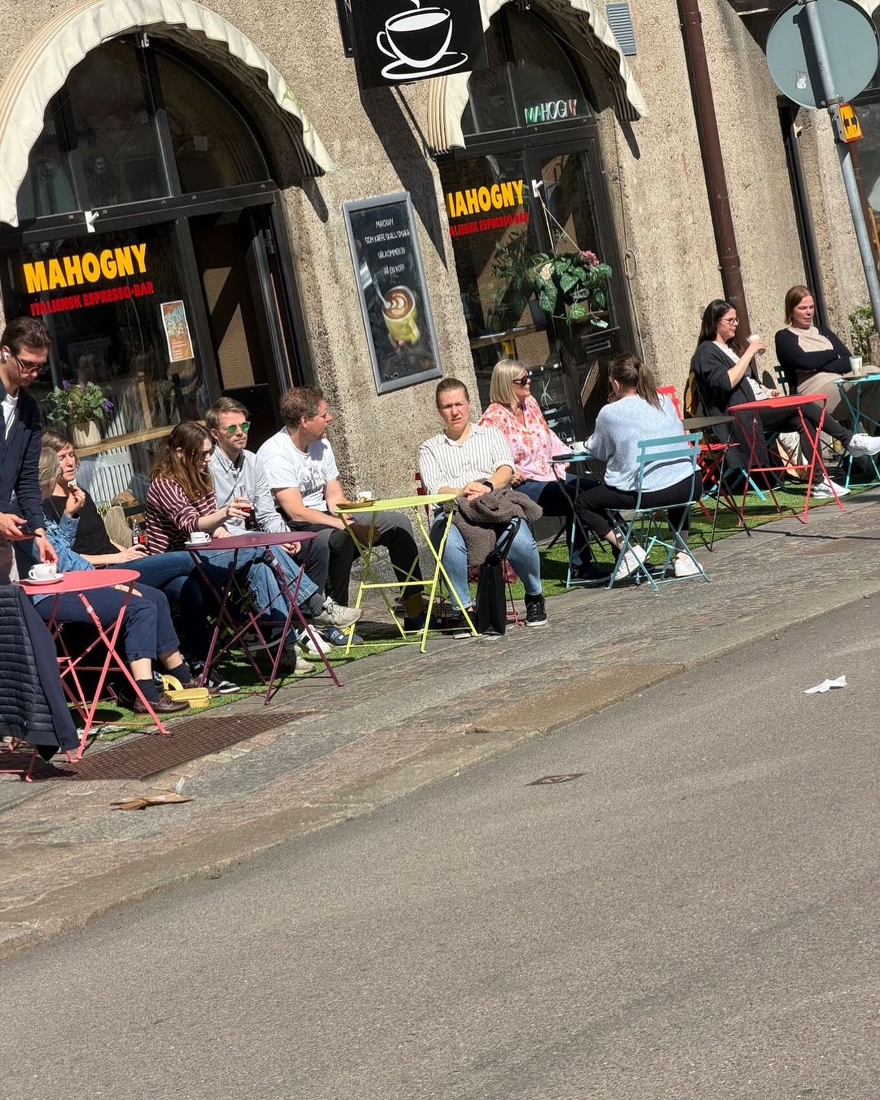 Gäster på Mahognys uteservering i solen på Kapellgatan